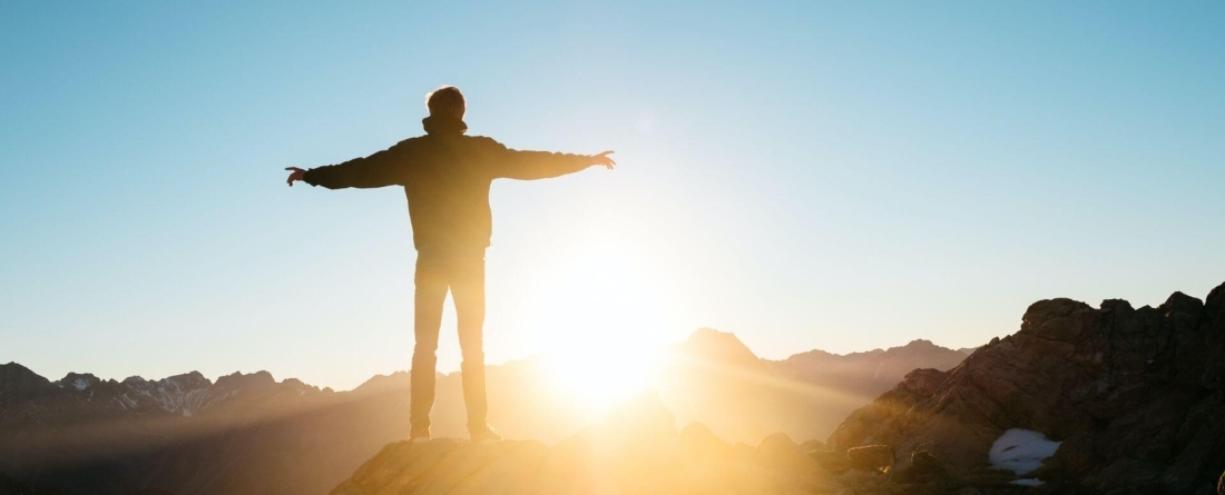 picture of person standing on mountain as sun is rising
